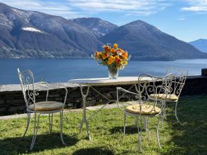 a table with a vase of flowers and two chairs at Casa Rocca Nera by HolAp in Ronco sopra Ascona