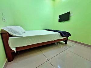 a small bed in a room with a tv on the wall at Sivasakthi Inn in Trivandrum