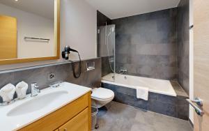 a bathroom with a sink and a toilet and a tub at ZermHaus - in the village center - very comfortable in Zermatt