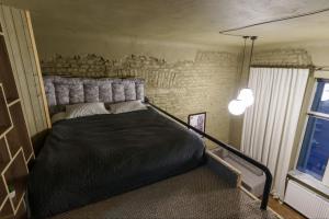 a bedroom with a large black bed with a brick wall at Апарат готель під ЗОЛОТИМ КОРАБЛЕМ двохрівнева студія in Chernivtsi