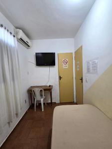 a room with a bed and a table and a television at Pousada SolMaris in João Pessoa