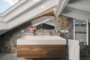 a bathroom with a large white tub in front of a wall at Attico Mansardato con terrazzo privato in Monza +9 photos