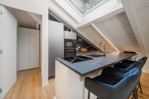 a kitchen with a sink and a counter with stools at Attico Mansardato con terrazzo privato in Monza