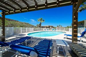 a swimming pool with blue reclining chairs next to it at Five O Clock Somewhere in Port Aransas