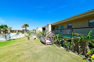 a house with a yard next to a pool at Five O Clock Somewhere in Port Aransas