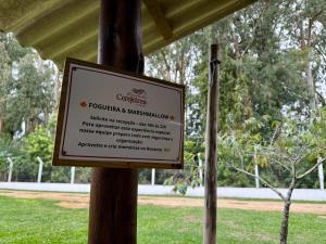 a sign on a pole in a park at Pousada Recanto das Cerejeiras in Rio Grande