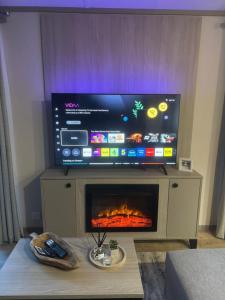 a flat screen tv above a fireplace in a living room at The Forest Lodge, Glen Eagles. in Auchterarder