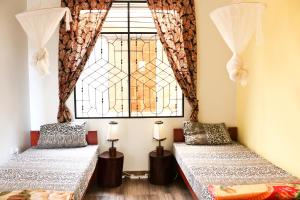 two beds in a room with a window at Rafiki Backpackers & Guesthouse in Moshi