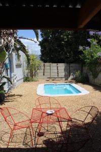 two chairs and a table in front of a swimming pool at Cozy and Central Bachelor Flat in Wellington +1 photo