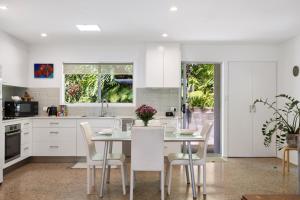 a kitchen with white cabinets and a table and chairs at Lucis Beach Retreat in Coolum Beach +26 photos