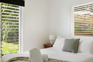 a white bedroom with a white couch and a window at Lucis Beach Retreat in Coolum Beach