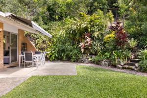 a patio with a table and chairs in a garden at Lucis Beach Retreat in Coolum Beach