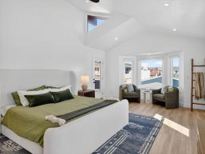 a white bedroom with a bed and a couch and chairs at Outrigger Beach Retreat in Oxnard