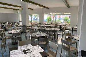a dining room filled with tables and chairs andwindows at Hotel Aron Rimini in Rimini