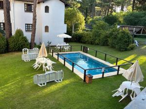 a pool with chairs and umbrellas next to a house at La Tonja in Pinamar