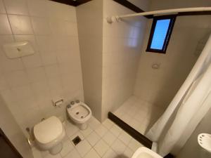 a white bathroom with a toilet and a shower at La Tonja in Pinamar