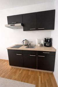a kitchen with black cabinets and a sink at baadenbergerstay A in Cologne