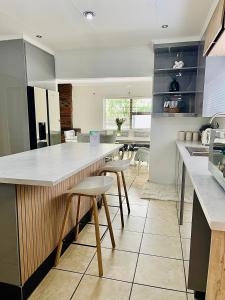 a kitchen with a large white counter and stools at 101 Marais Villa in Hartbeespoort