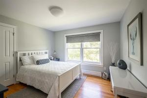 a white bedroom with a bed and a window at Starboard in Kennebunk