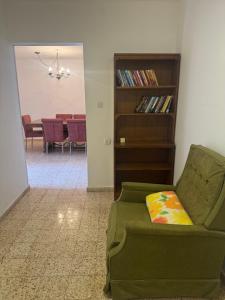 a living room with a green couch and a book shelf at צימר הר הגמל in Mitzpe Ramon