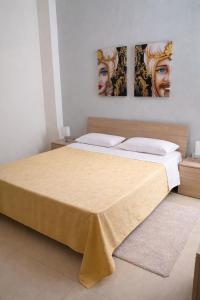 a bedroom with a large bed with two paintings on the wall at My Home Lampedusa in Lampedusa