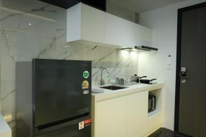a kitchen with a black refrigerator and white cabinets at Stylish Condo Near Nai Harn Beach Full Facilities Utopia M720 in Rawai Beach +7 photos