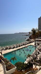 a group of people in a swimming pool next to the ocean at Suite con vista al mar Acapulco in Acapulco