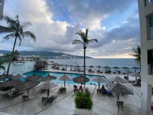 a view of a resort with a pool and palm trees at Suite con vista al mar Acapulco in Acapulco