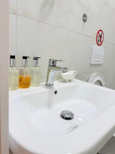 a white bathroom sink with two bottles of soap at 13 Daily apartments in Tirana +9 photos