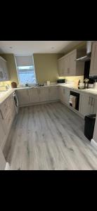 a large kitchen with white cabinets and a wooden floor at The Arch apartment in Bangor