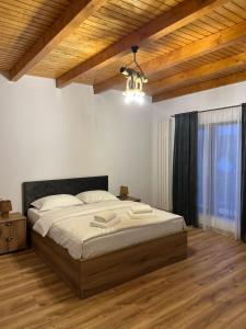 a bedroom with a large bed and a wooden ceiling at Casa Sima 2 in Curtea de Argeş