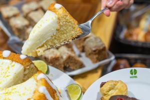 a person eating a piece of cake with a spatula at Hotel Nacional Inn Ubatuba - Praia das Toninhas in Ubatuba