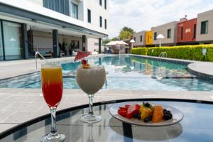 two drinks and a plate of food on a table near a swimming pool at Hotel Ronda Minerva in Guadalajara