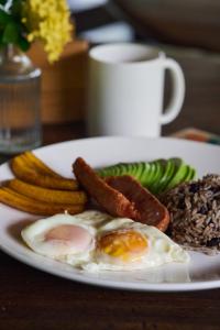 a plate with eggs sausage and vegetables on a table at Hotel Playa Negra in Playa Negra