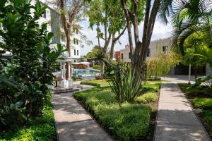 a garden with palm trees and a sidewalk at Hotel Ronda Minerva in Guadalajara