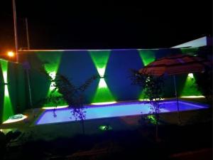 a swimming pool with green lights on a building at Casa PA parque das aguas in Bonito +2 photos
