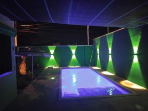 a swimming pool in a room with green lights at Casa PA parque das aguas in Bonito