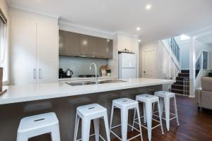 a kitchen with white cabinets and bar stools at Parkside Breeze in Rosebud in Rosebud