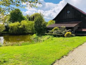 a barn in a field with a pond next to it at Haus mit Seeblick in Fürstenau