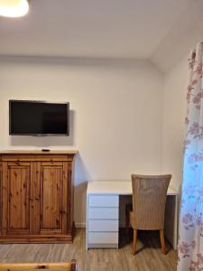 a room with a desk and a tv on a wall at Haus mit Seeblick in Fürstenau
