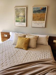 a bed with pillows and posters on the wall at Apartamento Sandy - wifi, ascensor, vistas al Mar,Amplio y Acogedor in Laxe