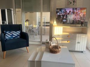 a living room with a blue chair and a tv at Apartment bay, Bougainville Bay Resort in Sarandë