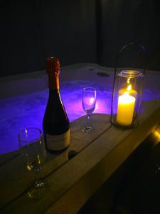 a bottle of wine with two glasses and a candle at Studio cosy - Jacuzzi inclus - À 5 min du Mans in Mulsanne