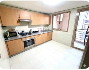 a kitchen with wooden cabinets and a stove top oven at Appartement avec vue sur parc et Wifi 100 Mo illimité ! in Fez
