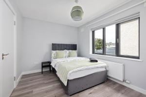 a white bedroom with a bed and a window at North Dublin Premier Oasis in Dublin