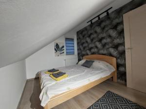 a bed in a room with a wall at Oaza Apartmani Jakovo HERA in Jakovo