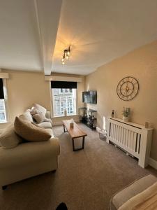 a living room with a couch and a clock on the wall at Charming 3 Bedroom High St Apartment in Much Wenlock