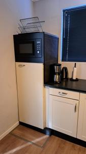 a kitchen with a microwave on top of a refrigerator at Woonhuis De Elsejan in Westerhaar-Vriezenveensewijk