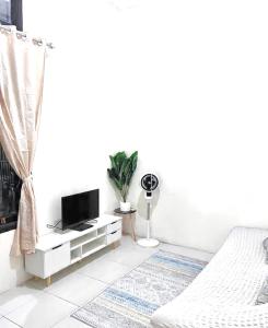 a white living room with a bed and a tv at Ibiza house pangandaran in Pangandaran