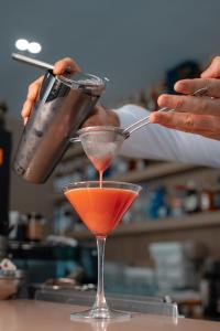 a person pouring a drink into a martini glass at Koral Boutique Hotel in Durrës